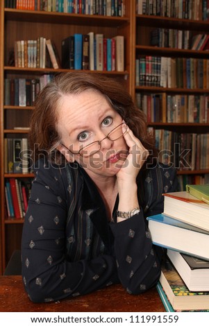 vertical orientation of happy smiling woman with glasses at a desk in a library setting / Happy to Help You!