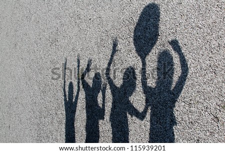 horizontal orientation of shadows of 4 kids playing together with gray gravel background and copy space / Shadow Play