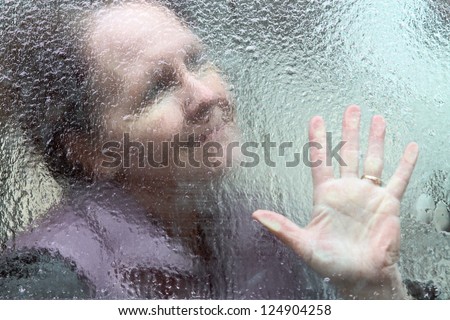 horizontal orientation close up outline of a smiling woman and her hand through a window covered in thick ice Hope through the Winter horizontal orientation close up outline of a smiling woman and her hand through a window covered in thick ice Hope through the Winter