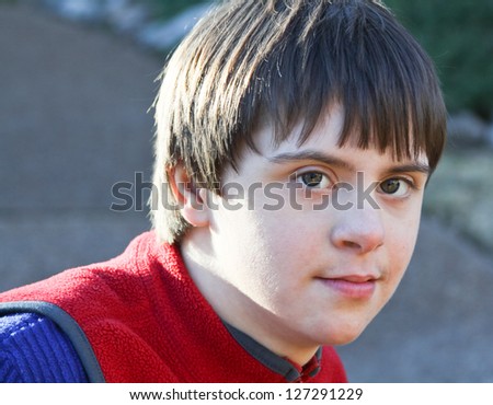 horizontal orientation close up portrait of smiling boy with autism and down\'s syndrome in outdoor setting / Dual Diagnosis
