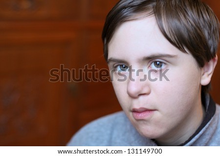 horizontal orientation close up of boy with autism and down\'s syndrome playing indoor with shallow depth of field and copy space / Autism affects almost Everyone