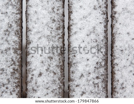 horizontal orientation extreme close up of slats on an iron table covered in fresh snow with a neutral background / Snowy Table Slats