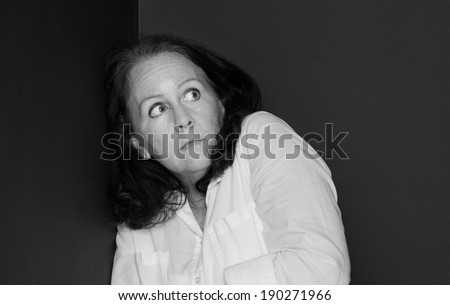 horizontal orientation close up black and white of a single woman with a fearful, paranoid look on her face, with copy space / Paranoia in Black and White