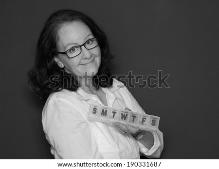 horizontal orientation, black and white, close up of a single woman with dark hair and glasses holding a pill box, with copy space