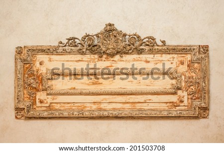 horizontal orientation close up of a weathered, vintage, wooden plaque with scrollwork in warm tones and neutral background, with copy space / Vintage Wooden Plaque