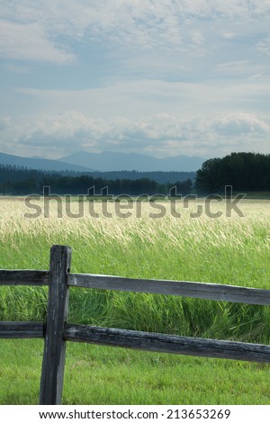 vertical orientation looking out on meadows with a wooden fence in the foreground, and mountains and sky in the background and copy space / Northern Idaho - Vertical Orientation