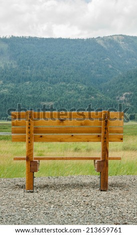 vertical orientation of a single, empty, wooden bench in the foreground, with the majestic Selkirk Mountain Range in the background, with copy space / Spectacular Northern Idaho - Vertical