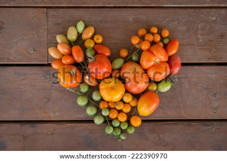 horizontal orientation close up of a variety of colorful tomatoes in the shape of a heart, on a neutral wooden background / Heart Healthy - Horizontal