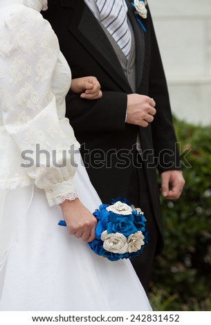 vertical orientation close up of the torsos of a man and a woman in wedding attire, arm in arm, with copy space, in an outdoor setting / Man and Wife - Vertical