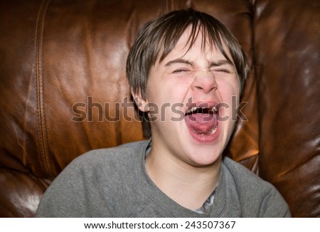 horizontal orientation close up of a teenage boy with autism and down\'s syndrome screaming as he has a meltdown / Teenage Boy with Autism has a Meltdown
