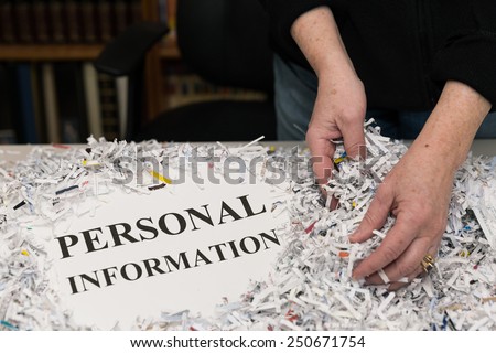 horizontal orientation close up of a woman\'s hands gathering shredded paper to recycle with the words PERSONAL INFORMATION shown / Protecting Personal Information