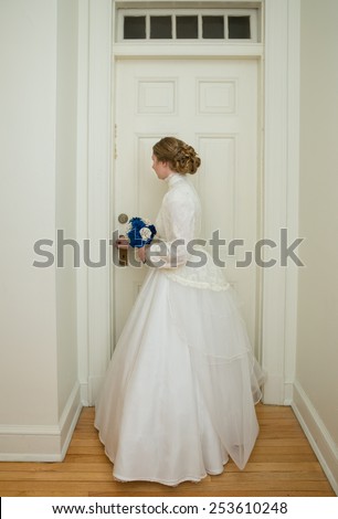 vertical orientation color photo of a beautiful, young, bride, dressed in an antique vintage gown, standing at the interior doorway of a vintage building / Ready for Marriage