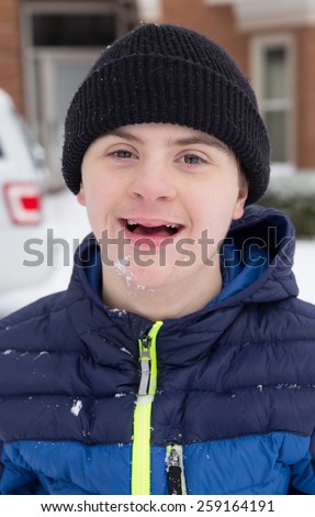 vertical orientation image of a happy, smiling, teenage boy with autism and down\'s syndrome, outside, playing in the snow / Winter Play Activities