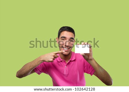 Portrait of a young man wearing a pink polo shirt. He is holding a white card. Over green monochrome background. Ready to use in a commercial campaign