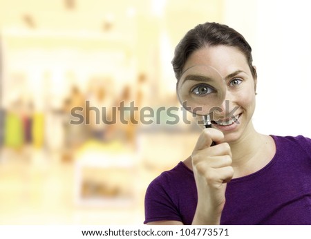 Beautiful young woman looking through a magnifying glass over a business center background