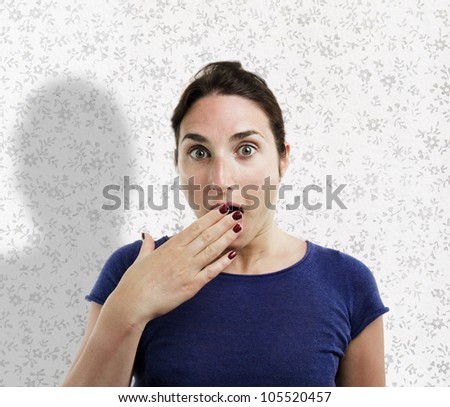 Young woman covering her mouth with her hand over flowery background