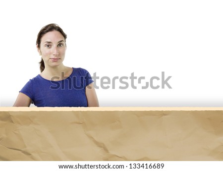 Young confident woman peeping out from a brown torn paper