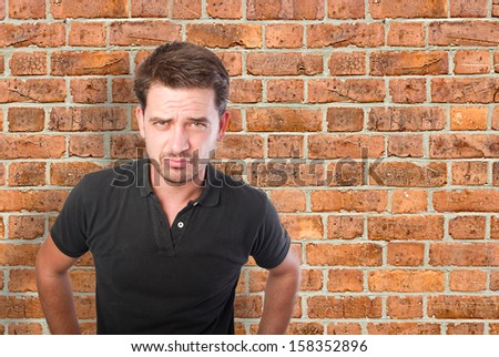 Young man looking upset over a bricks wall