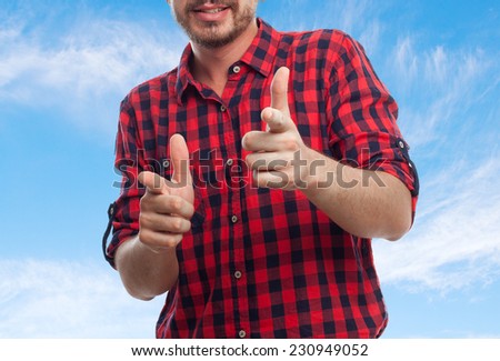 Young man with squares shirt over clouds background. Looking happy