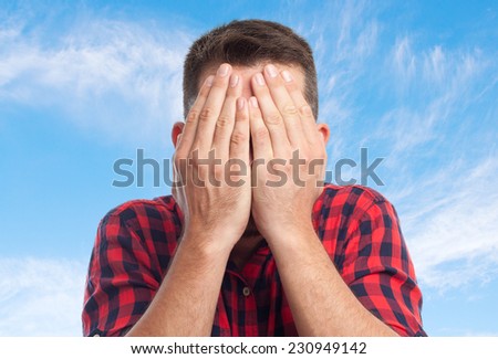 Young man with squares shirt over clouds background. Looking scared