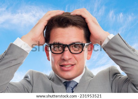 Young business man with grey suit over clouds background. Looking scared