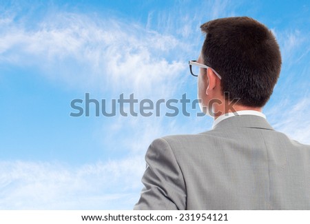 Young business man with grey suit over clouds background. Giving his back