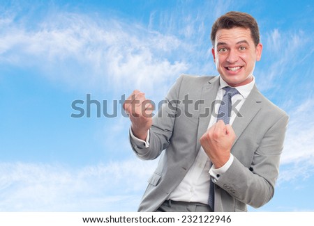 Young business man with grey suit over clouds background. Ready to fight