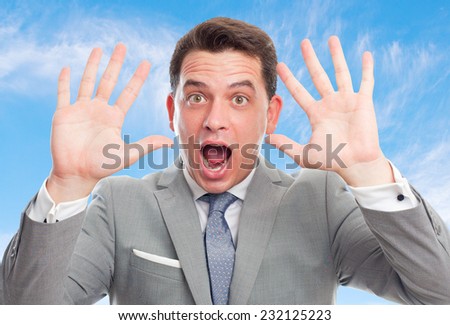 Business man with grey suit over clouds background. Looking surprised