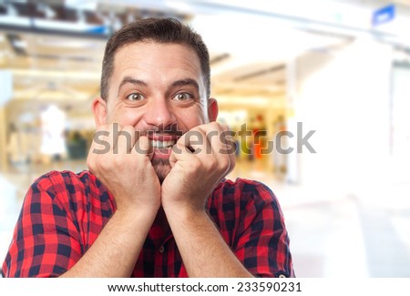 Man with red shirt over shopping center background. Looking scared