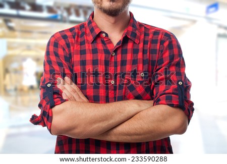 Man with red shirt over shopping center background. With his arms crossed