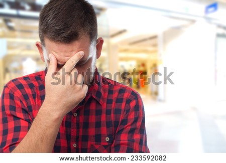 Man with red shirt over shopping center background. Looking tired