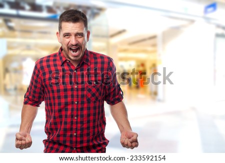 Man with red shirt over shopping center background. Looking upset