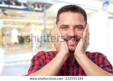 Man with red shirt over shopping center background. Looking happy