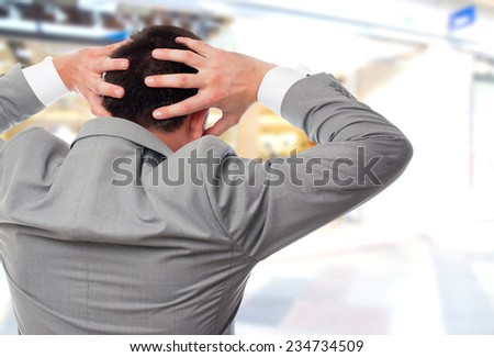 Business man over shopping center background. Giving his back and looking surprised