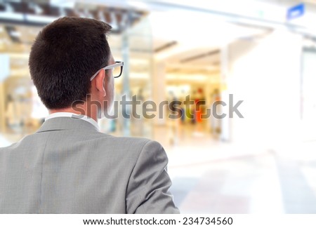 Business man over shopping center background. Giving his back