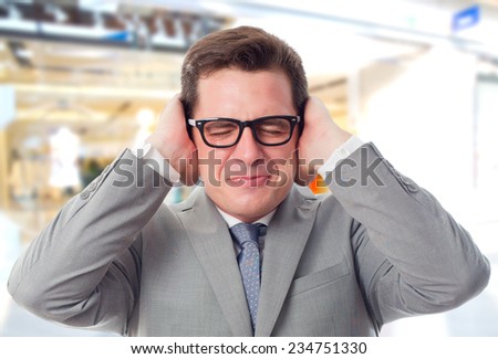 Business man over shopping center background. Upset because of the noise