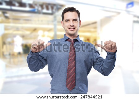 Man wearing a blue shirt and red tie. He is pointing to himself