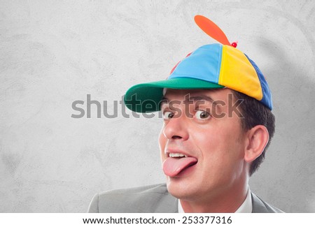 Business man with grey suit wearing a colorful cap. He is looking funny. Over concrete texture
