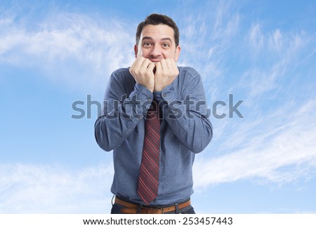 Man wearing a blue shirt and red tie. He is looking afraid. Over clouds background