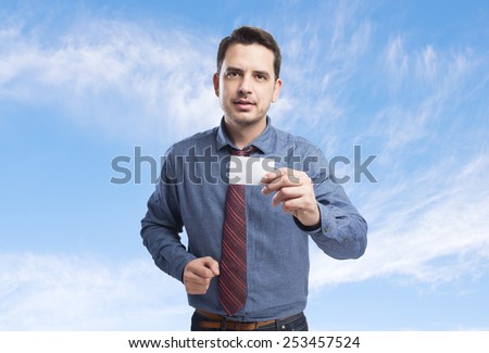 Man wearing a blue shirt and red tie. Holding a white card. Over clouds background