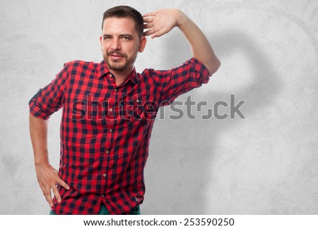Man with red squares shirt. He is doing a funny pose. Over concrete wall