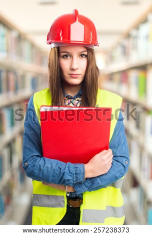 Trendy young woman wearing a red helmet and holding a red folder. Over library background