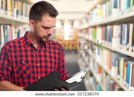 Man with red squares shirt. He is reading from a black folder. Over library background