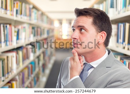 Business man with grey suit. He is looking funny. Over library background