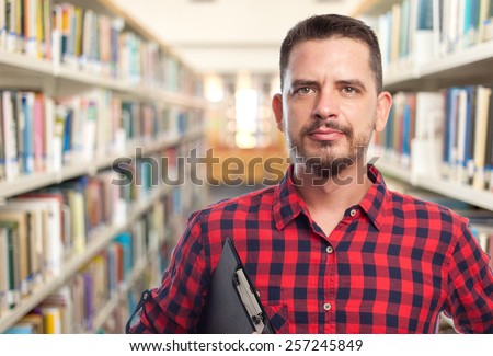 Man with red squares shirt. He is holding a black folder. Over library background