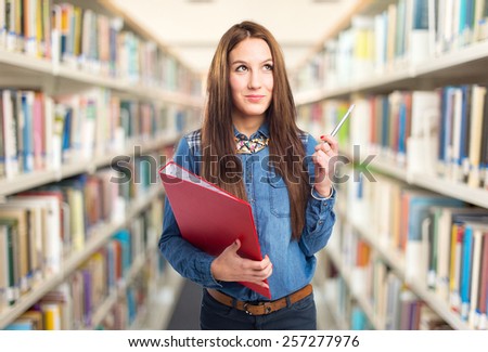 Trendy young woman looking serious holding a red folder and a pen. Over library background
