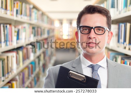 Business man with grey suit. He is wearing glasses and holding a folder. Over library background