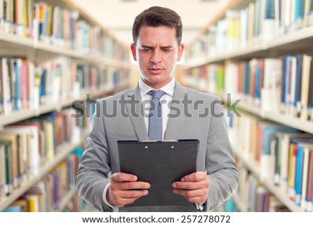 Business man with grey suit. He is holding a black folder. Over library background