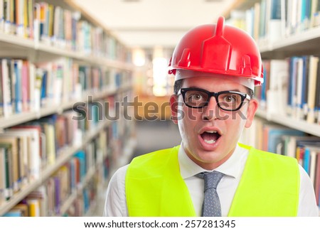Architect man with red helmet. He is looking funny. Over library background