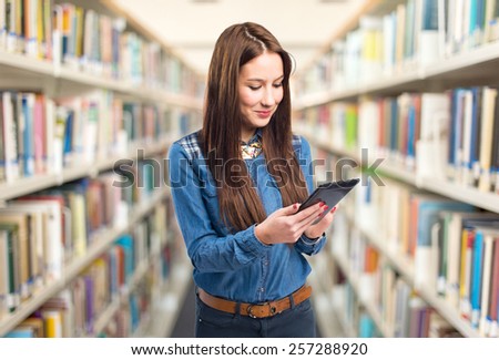 Trendy young woman using a tablet. Over library background